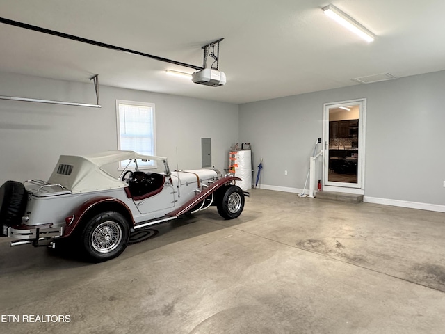 garage featuring a garage door opener, gas water heater, and electric panel