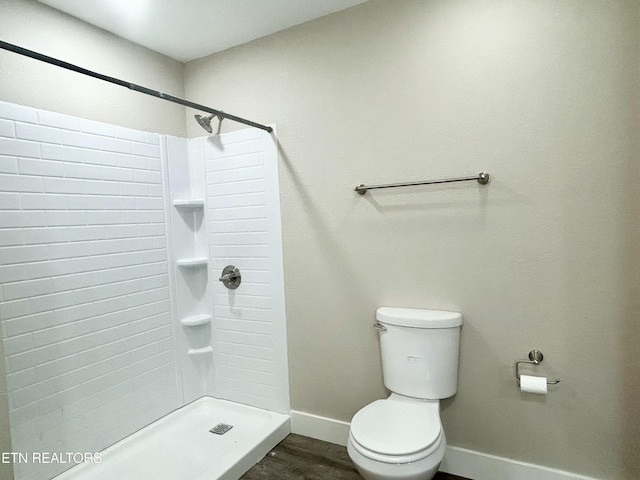 bathroom with hardwood / wood-style floors, a shower, and toilet