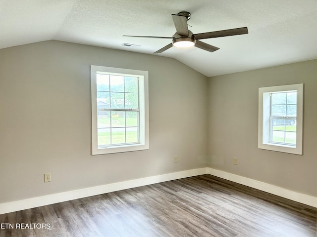 spare room with lofted ceiling, plenty of natural light, hardwood / wood-style floors, and a textured ceiling