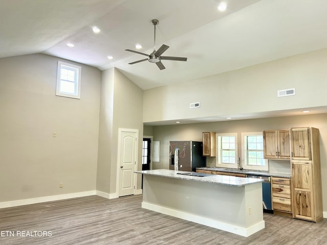 kitchen with sink, light hardwood / wood-style flooring, stainless steel appliances, a center island, and light stone countertops