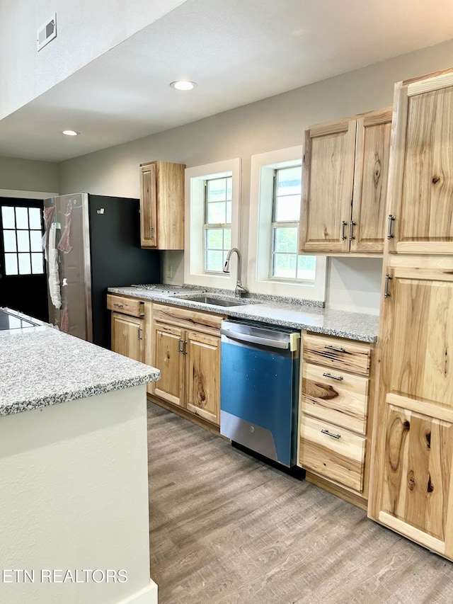 kitchen with sink, light hardwood / wood-style flooring, appliances with stainless steel finishes, light stone countertops, and light brown cabinetry