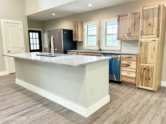 kitchen with light stone counters, light hardwood / wood-style flooring, stainless steel appliances, and a kitchen island