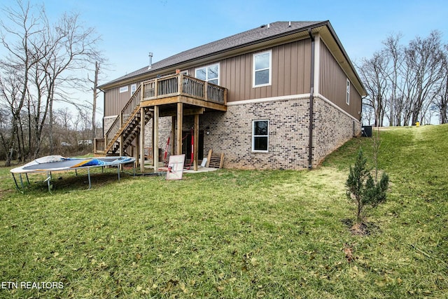 back of house featuring a trampoline, a wooden deck, a yard, and central AC