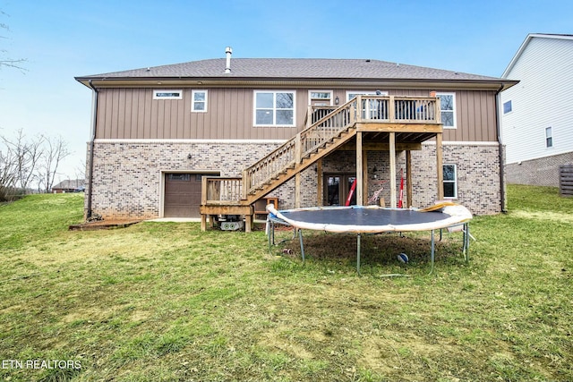 back of house featuring a trampoline, a yard, a garage, and a deck