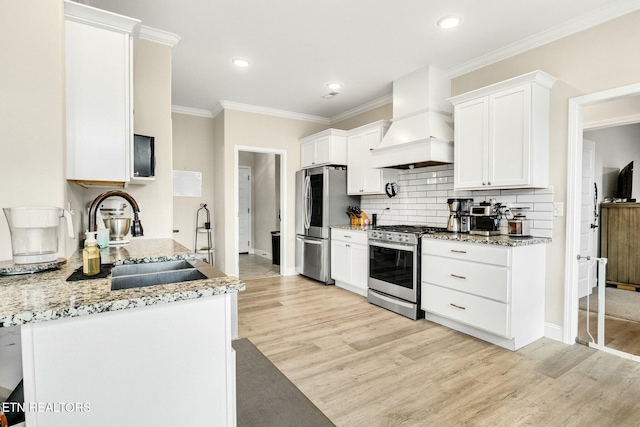 kitchen featuring sink, appliances with stainless steel finishes, white cabinetry, premium range hood, and light stone counters