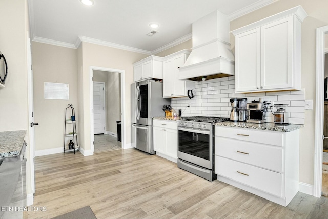 kitchen featuring premium range hood, appliances with stainless steel finishes, white cabinetry, light hardwood / wood-style floors, and light stone countertops