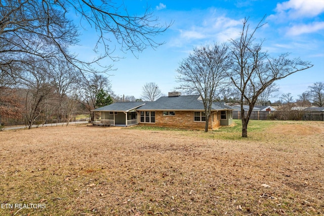 back of house featuring a sunroom and a lawn