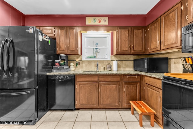 kitchen with tasteful backsplash, sink, light tile patterned floors, and black appliances