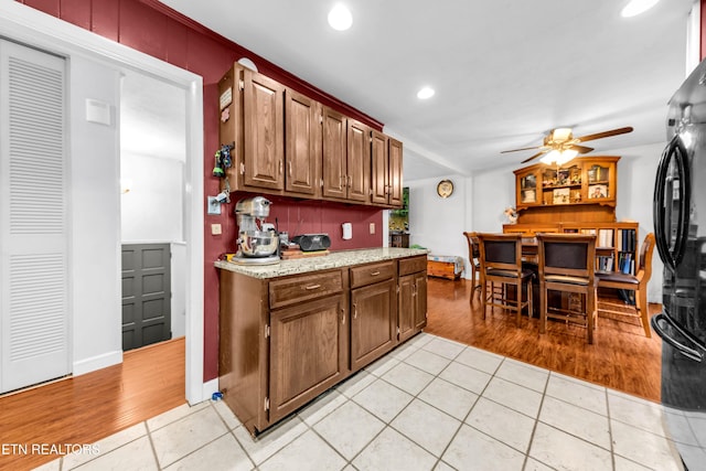 kitchen with light tile patterned flooring, black fridge, backsplash, and ceiling fan