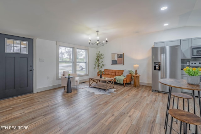 foyer entrance featuring lofted ceiling, a chandelier, and light hardwood / wood-style floors