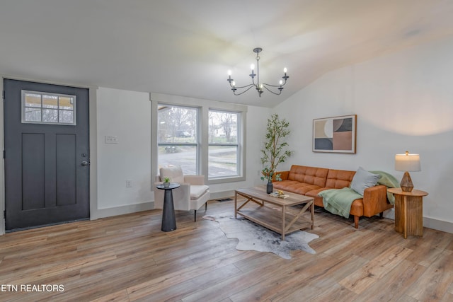 living room with vaulted ceiling, light hardwood / wood-style floors, and a notable chandelier