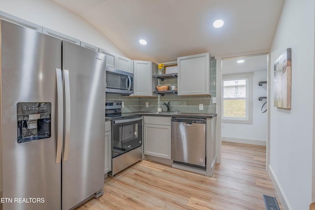 kitchen with lofted ceiling, sink, stainless steel appliances, light hardwood / wood-style floors, and decorative backsplash