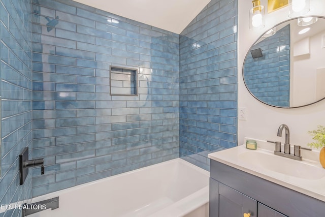 bathroom with vanity, tiled shower / bath combo, and vaulted ceiling