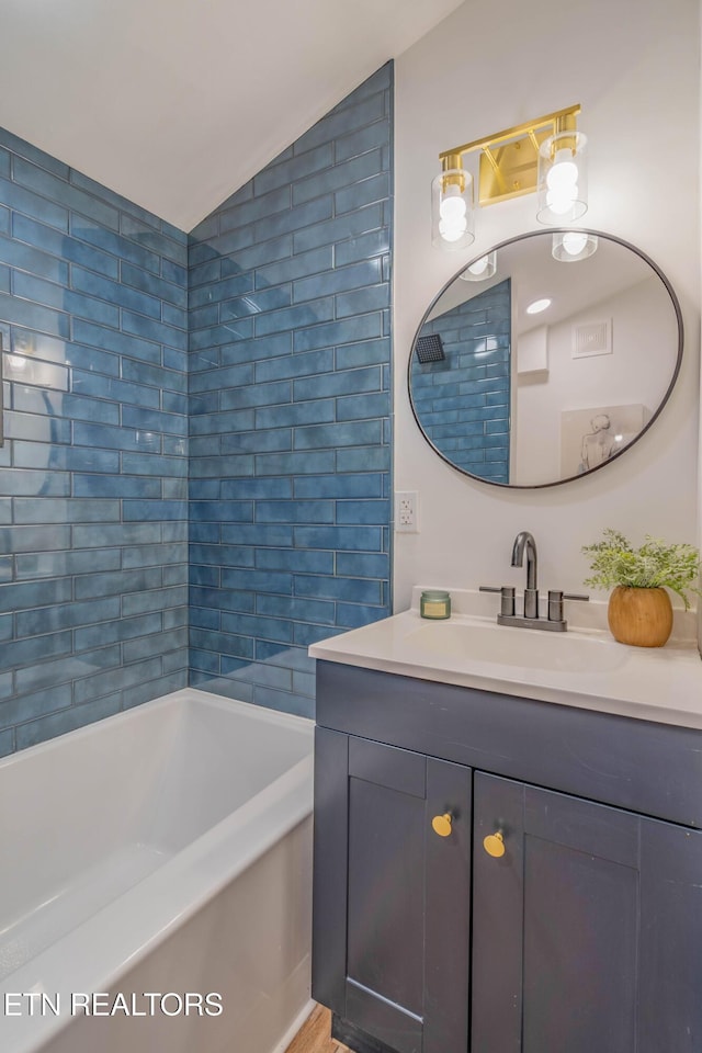 bathroom featuring lofted ceiling, a bathtub, and vanity