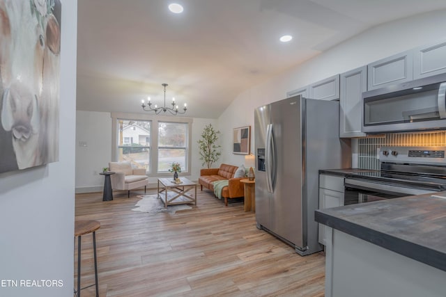 kitchen with lofted ceiling, appliances with stainless steel finishes, gray cabinets, and light hardwood / wood-style flooring