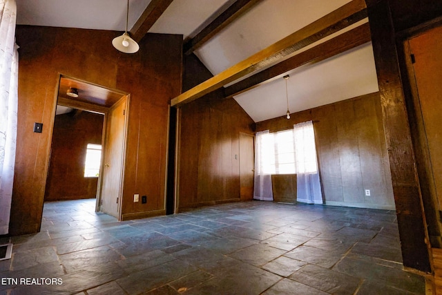 empty room with stone tile flooring, beamed ceiling, visible vents, and wooden walls