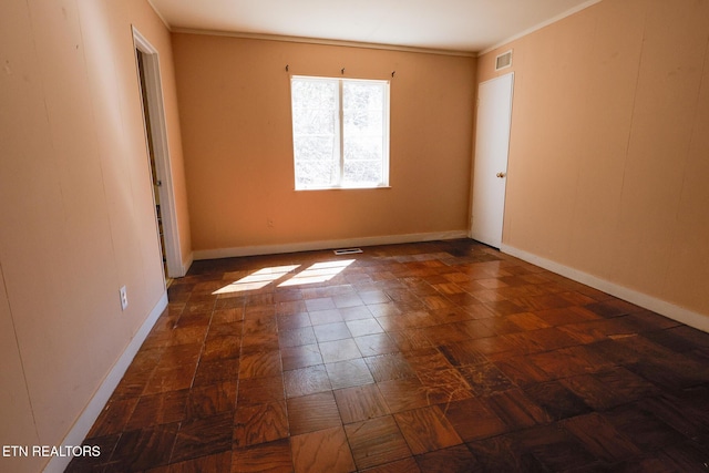 empty room featuring visible vents, baseboards, and ornamental molding