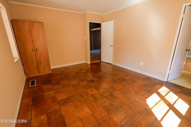 unfurnished bedroom with visible vents, baseboards, and ornamental molding