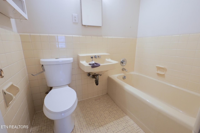 bathroom featuring tile patterned flooring, tile walls, toilet, and a bathtub