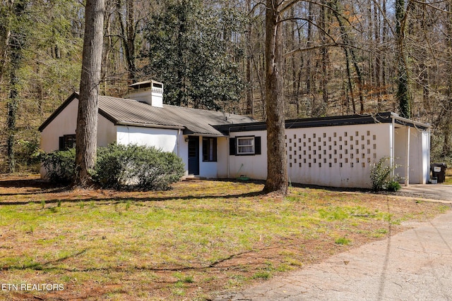 mid-century home featuring metal roof, a chimney, and a front lawn