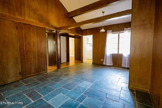 unfurnished room with stone tile floors, wooden walls, and beamed ceiling