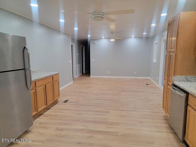 kitchen with light stone countertops, light hardwood / wood-style flooring, stainless steel appliances, and ceiling fan