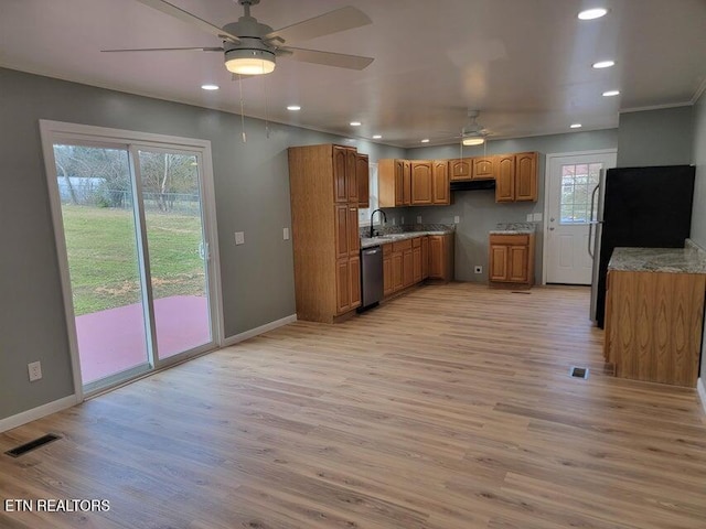 kitchen featuring appliances with stainless steel finishes, sink, ceiling fan, light hardwood / wood-style floors, and light stone countertops