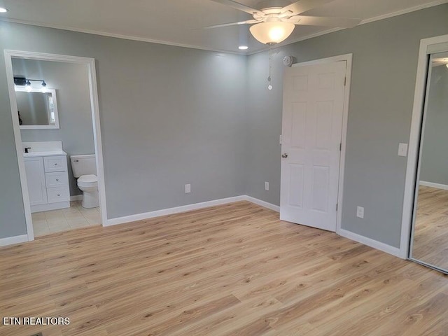 unfurnished bedroom featuring crown molding, connected bathroom, and light hardwood / wood-style floors