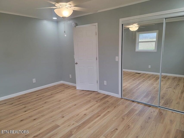 unfurnished bedroom with crown molding, a closet, ceiling fan, and light wood-type flooring