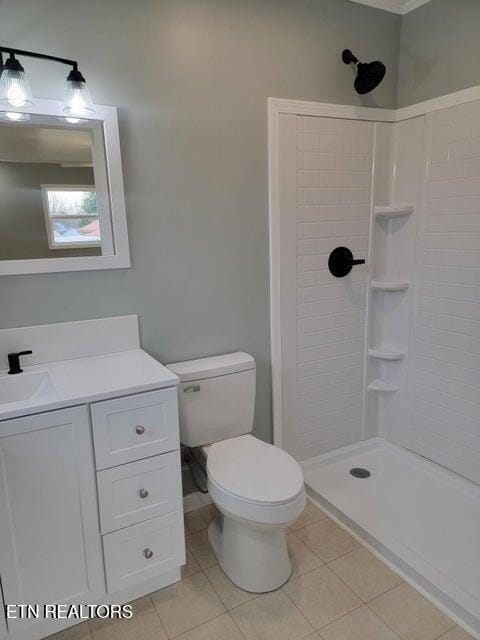 bathroom with vanity, tile patterned floors, toilet, and tiled shower