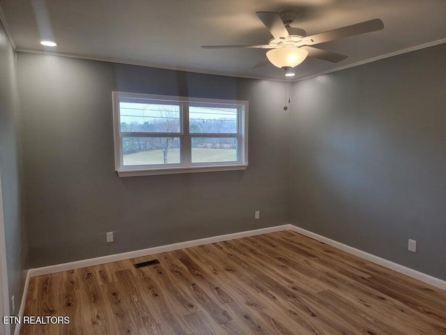 empty room featuring hardwood / wood-style flooring, ornamental molding, and ceiling fan