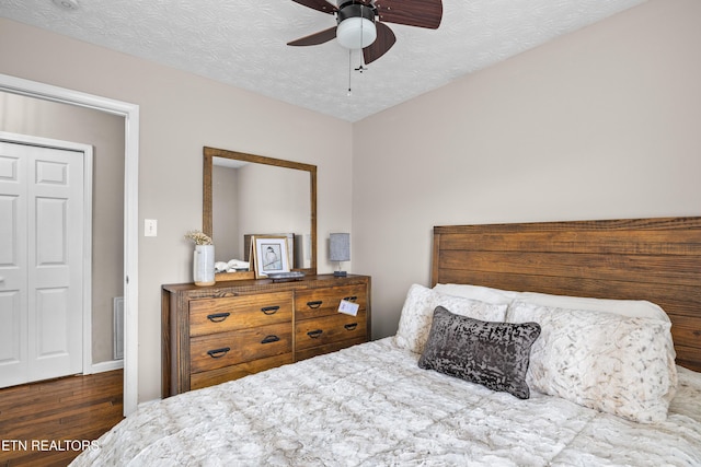 bedroom with a textured ceiling, dark hardwood / wood-style floors, and ceiling fan