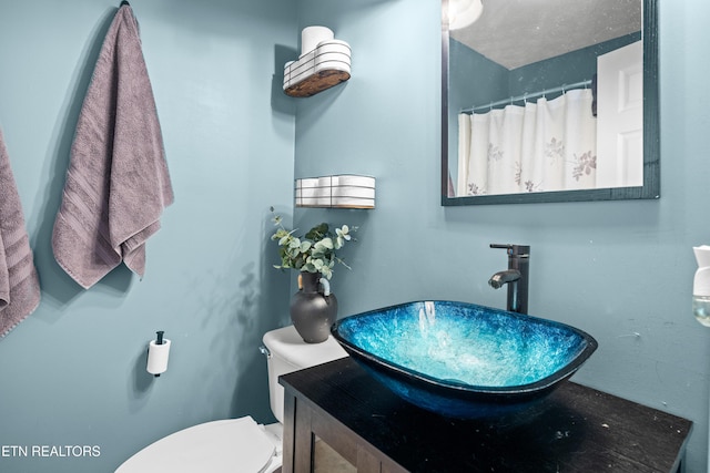 bathroom featuring toilet, vanity, and a shower with shower curtain