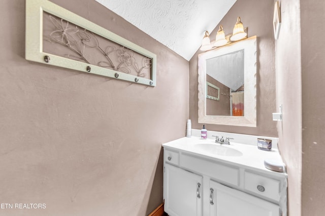 bathroom featuring vanity, vaulted ceiling, and a textured ceiling