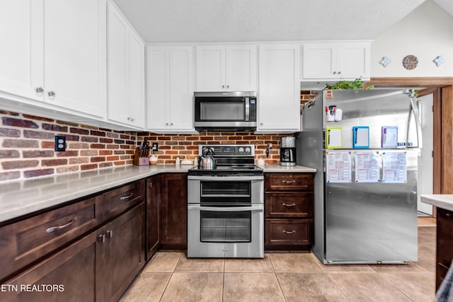 kitchen featuring dark brown cabinetry, white cabinetry, a textured ceiling, light tile patterned floors, and stainless steel appliances