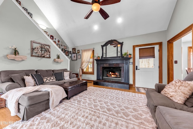 living room with a healthy amount of sunlight, lofted ceiling, a fireplace, and wood-type flooring