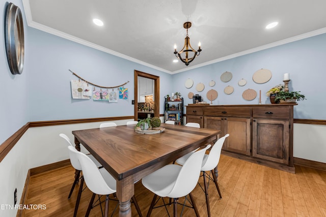 dining area with crown molding, a chandelier, and light hardwood / wood-style floors