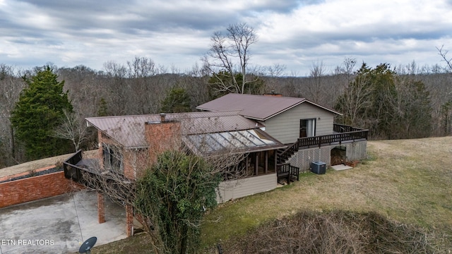 exterior space with central AC, a deck, and a lawn