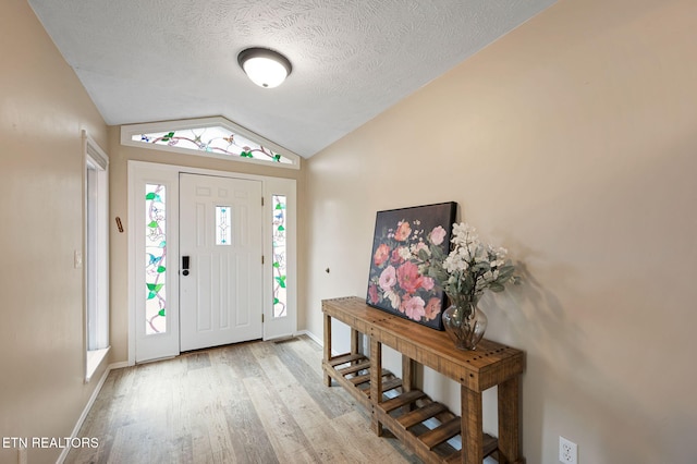 entryway with lofted ceiling, light hardwood / wood-style flooring, and a textured ceiling