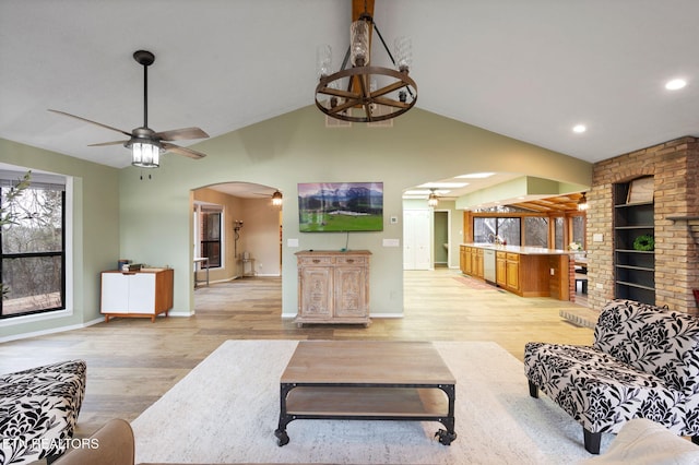 living room with ceiling fan, vaulted ceiling, and light wood-type flooring