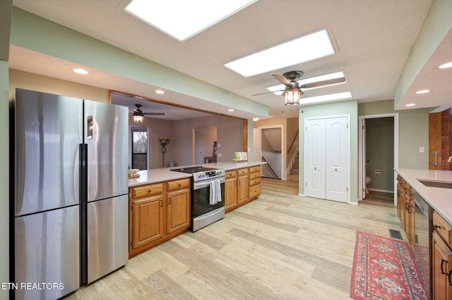 kitchen with appliances with stainless steel finishes, sink, ceiling fan, and light hardwood / wood-style flooring