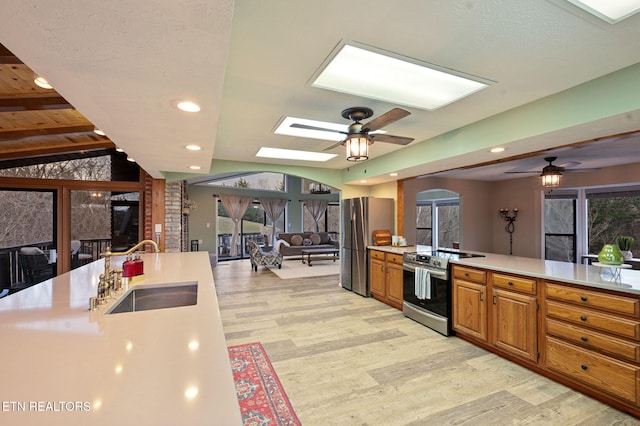 kitchen with ceiling fan, appliances with stainless steel finishes, sink, and light hardwood / wood-style flooring