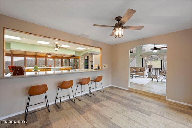 kitchen with ceiling fan, light hardwood / wood-style floors, and a breakfast bar area