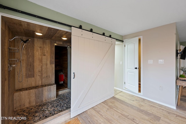 unfurnished bedroom with light hardwood / wood-style floors and a barn door