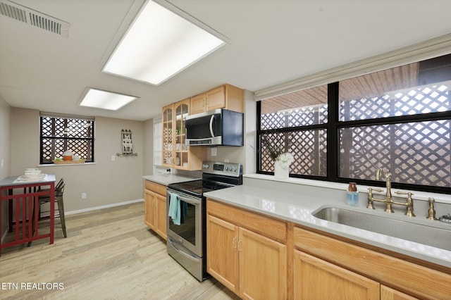 kitchen featuring light brown cabinetry, sink, stainless steel appliances, and light hardwood / wood-style floors