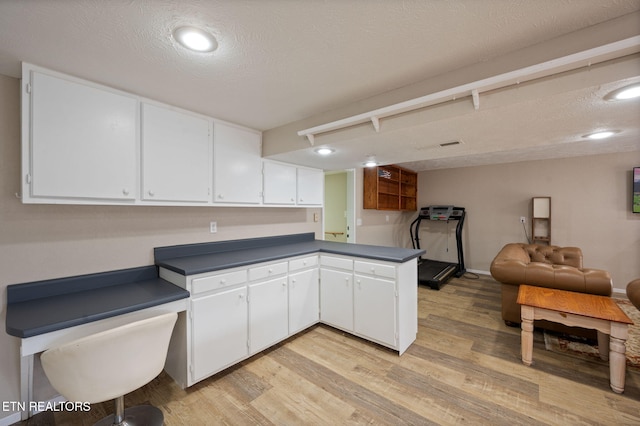 kitchen featuring white cabinetry, a textured ceiling, light hardwood / wood-style floors, and kitchen peninsula