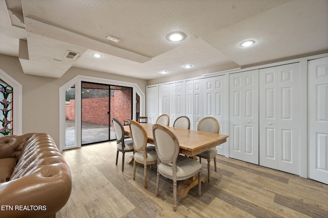 dining space featuring a textured ceiling and light wood-type flooring