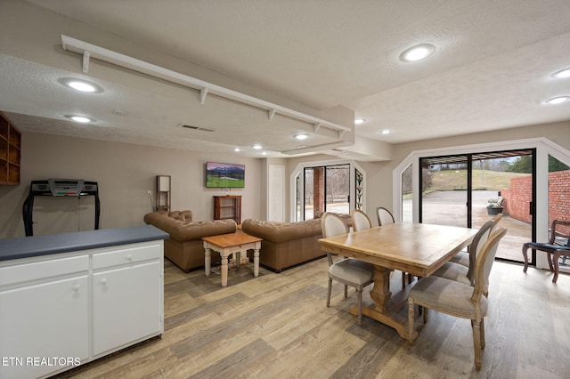 dining area featuring a textured ceiling and light wood-type flooring