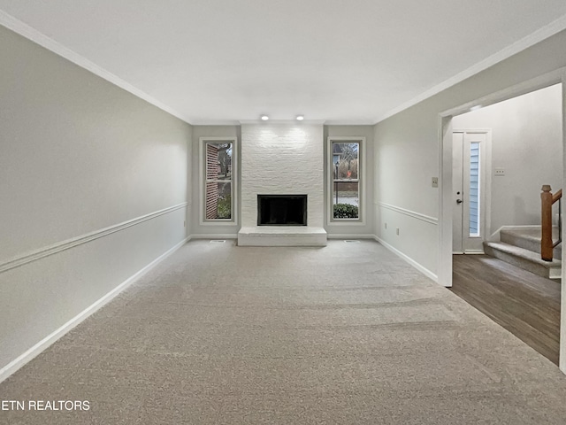 unfurnished living room with carpet floors, ornamental molding, and a large fireplace