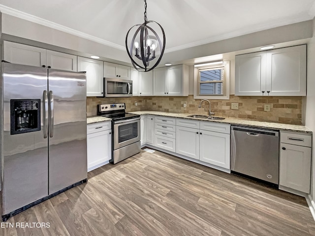 kitchen featuring appliances with stainless steel finishes, sink, pendant lighting, and white cabinets